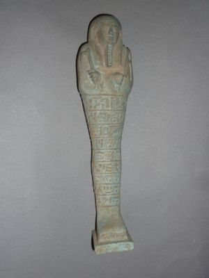 une statue égyptienne représentant un homme à la tête imposante, les mains posées sur la poitrine