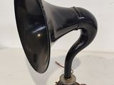 un vieux gramophone noir posé sur un support, devant un fond blanc