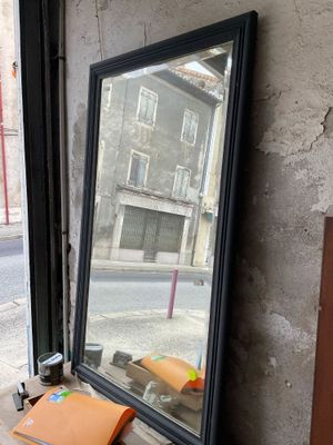 un miroir posé sur le rebord d'une fenêtre, devant celle-ci