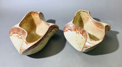 une paire de pantoufles en céramique blanches et marron posées sur une surface grise
