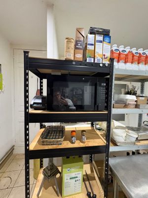 a microwave on a shelf in the middle of a kitchen