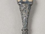 a silver spoon with an egg in it on a white surface