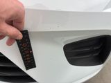 a person holding a ruler in front of the front of a car