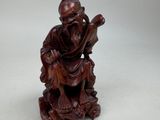 an image of a wooden statue of a man sitting on a rock