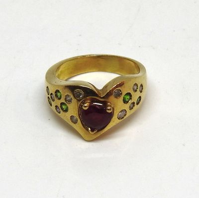 une image représentant une bague en or sertie d'une grenat en forme de cœur, entourée de pierres vertes et violettes