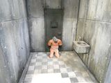 un petit ours en peluche assis dans un coin d'une cellule de prison