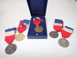 three medals and a medal in a blue case on a table