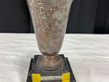 un vase en argent posé sur un socle en marbre, sur une table