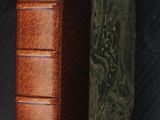 un livre relié en cuir posé sur une table noire, à côté d'une horloge