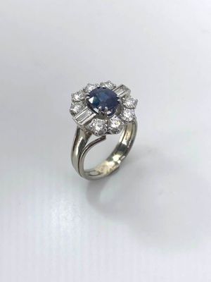 a close up of a diamond and sapphire ring on a white surface
