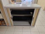 une petite armoire dont la porte est ouverte et dont le fond repose à même le sol