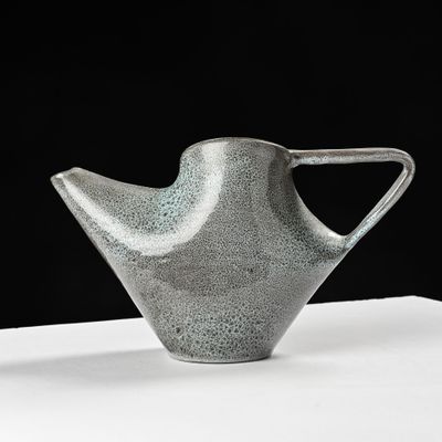 gray vase on a white table with a black background