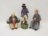 trois figurines représentant des personnes sont assises sur une surface blanche