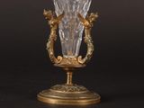 a glass vase on a stand on a black background