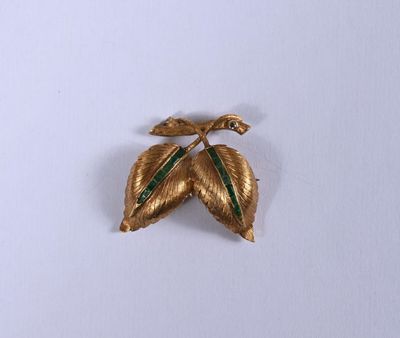 une broche en or ornée d'une feuille verte