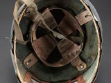 an old helmet is sitting on a metal stand on a black surface
