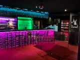 Des lumières violettes et vertes éclairent l'espace bar d'un restaurant