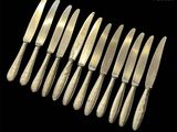 six silverplated knives and six knives on a black background