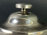a silver pot with a lid on a table