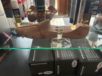 deux sabots en bois posés sur une étagère en verre, à côté d'un coffret de parfum