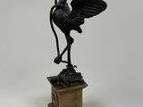 a bronze statue of a bird on a pedestal on a white background