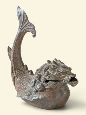 statue d'un poisson, la bouche ouverte, posée sur un bol