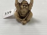 un gros plan d'une figurine de singe posée sur une surface blanche