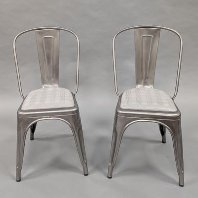 pair of silver metal chairs with wicker backrests