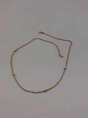 un bracelet en chaîne d'or orné de perles sur fond blanc
