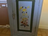 a cabinet with a painting on it in a room