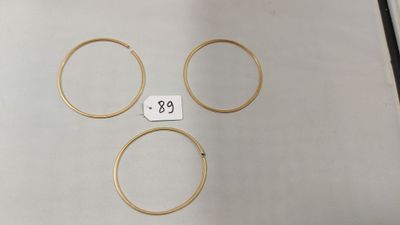 un gros plan sur quatre bagues en or posées sur une table, avec une étiquette de prix