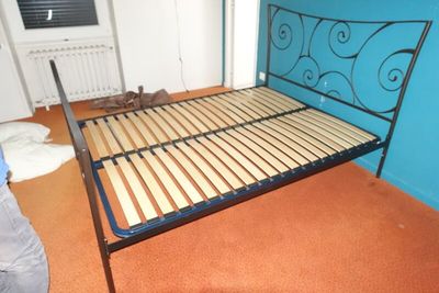un cadre de lit en métal avec des lattes en bois dans une chambre