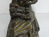 an old bronze statue of a woman holding a baby in her lap