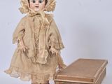 an old fashioned doll with a hat and dress next to a box