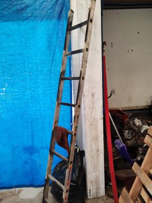 une échelle appuyée contre un mur, à côté d'une bâche bleue