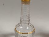 a clear glass bottle with a gold trim around the neck