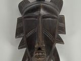 a close up of a wooden mask hanging on a wall