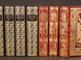 three old books are lined up in a row on a table