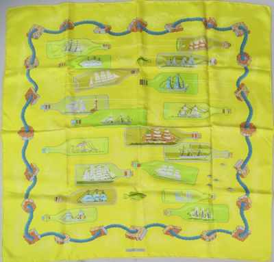 une écharpe jaune sur laquelle est représenté un motif de bateaux dans des bouteilles
