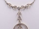 a close up of a necklace on a white surface with a diamond