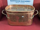une grande casserole en cuivre posée sur une table rouge
