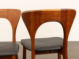two wooden chairs with black leather seats in a room