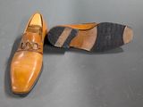 pair of brown shoes on a grey surface with a black and white stripe