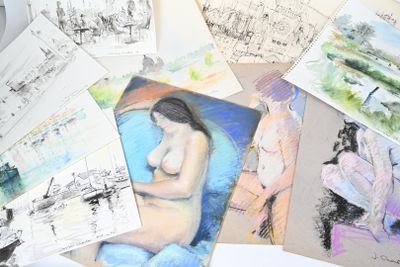une pile de dessins posée sur une table recouverte de feuilles de papier