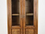 une vitrine ancienne en bois, dotée de portes vitrées et d'étagères