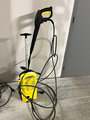 un pot de peinture jaune et noir posé par terre, près d'un mur blanc