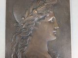 a picture of a bronze plaque of a woman with a wreath on her head