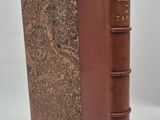an old book with a brown cover sitting on top of a white table