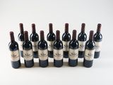 six bottles of red wine lined up in a row on a white surface