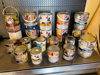 de nombreux pots de peinture posés sur une étagère dans un magasin